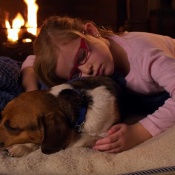 Little girl and adopted dog cuddling in front of flireplace